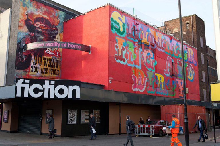 colourful large scale lettering on a bright red hoarding in Romford, spelling out "shimmering and dirty"