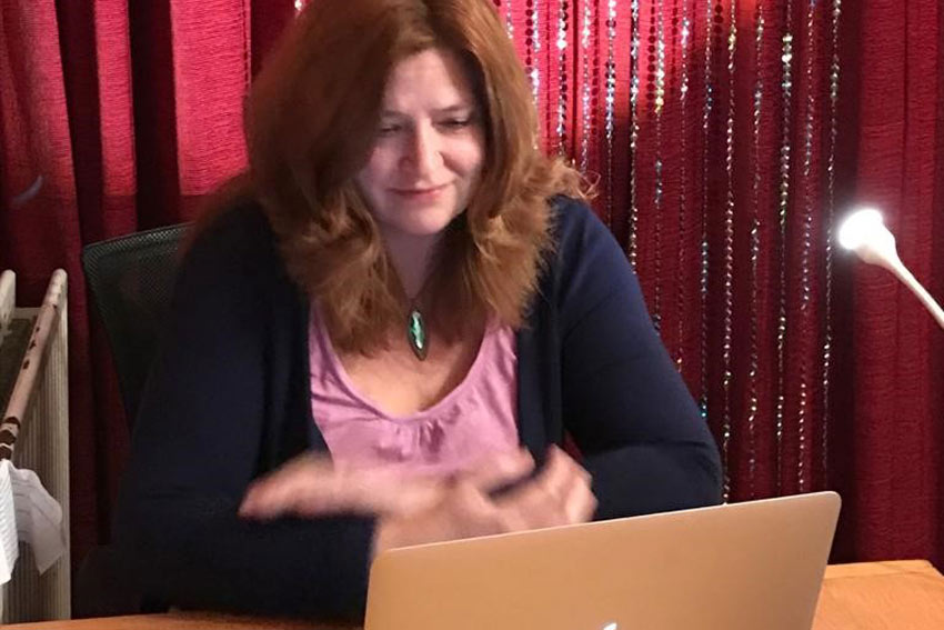 Andrea campanale seated behind a laptop with red curtain backdrop