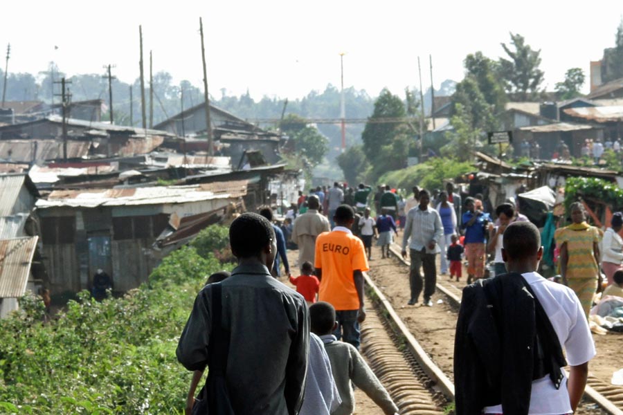 People walking along a rail track in Kibera, Nairobi, Kenya