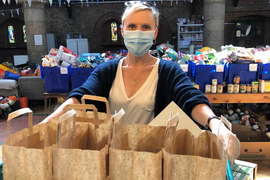 woman with tray of brown paper bags, food crates in backgournd