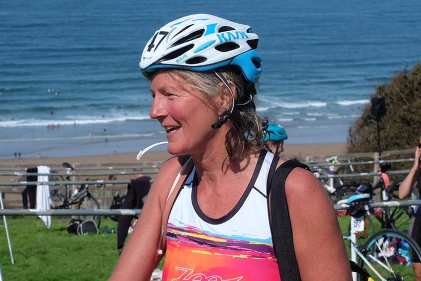 Sun tanned woman in cycling helmet by the sea