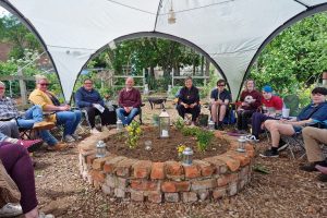 group seated in circle around a circular raised bed under a large gazebo