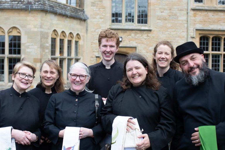 Smiling group in cassocks without dog collars, holding new stoles
