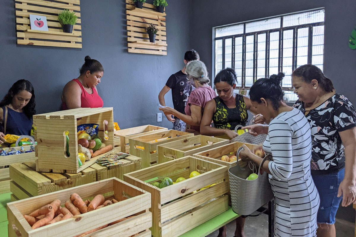 Brazilian women gather round crates of fresh vegetables